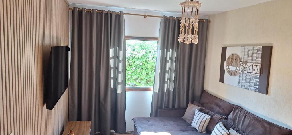 een woonkamer met een bank en een raam bij apartamento águas de lindoia itaigara in Águas de Lindóia