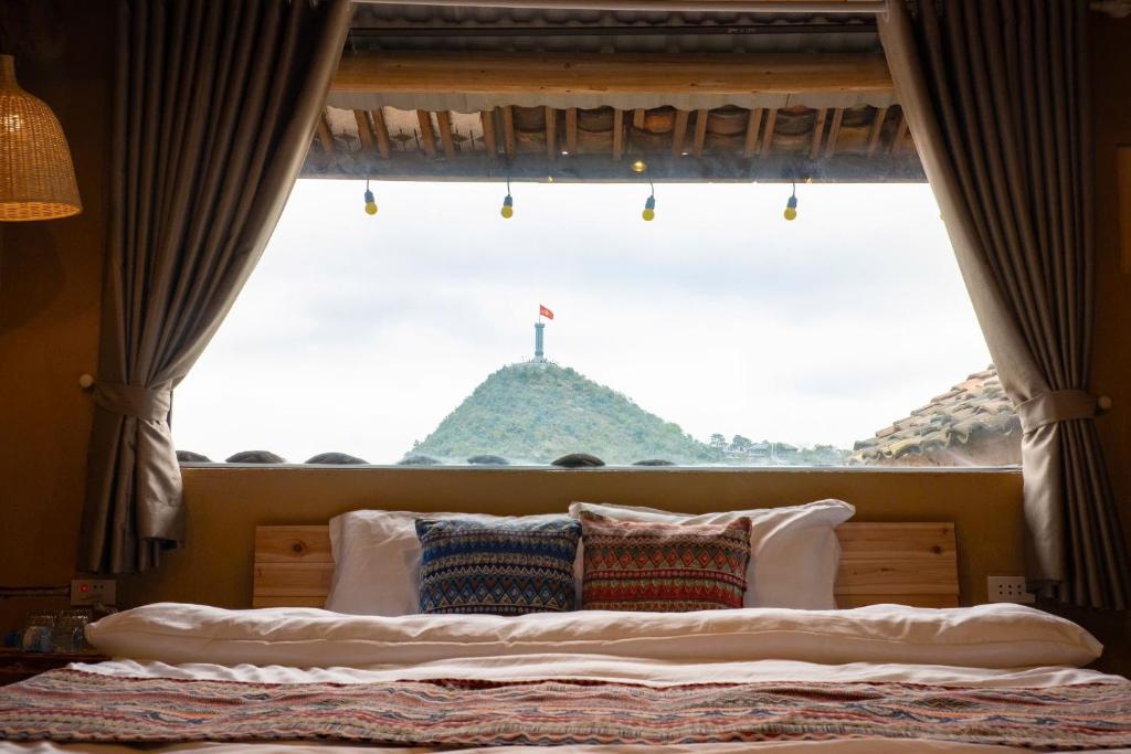 a bed with a window with a view of a mountain at Vị Lư homestay in Dồng Văn