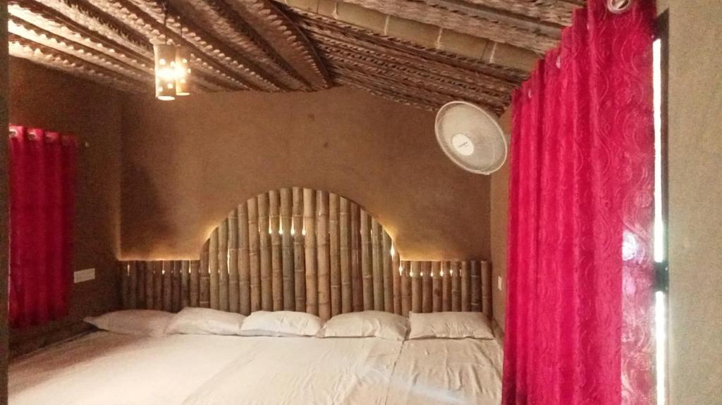 a bedroom with a large bed with red curtains at Vihara Mud House in Marayoor