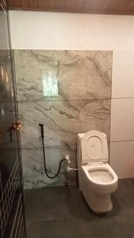 a bathroom with a toilet and a stone wall at Vihara Mud House in Marayoor