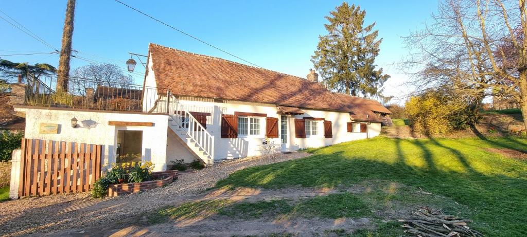 a white house with a fence and a yard at Gite de l'étang in La Puisaye