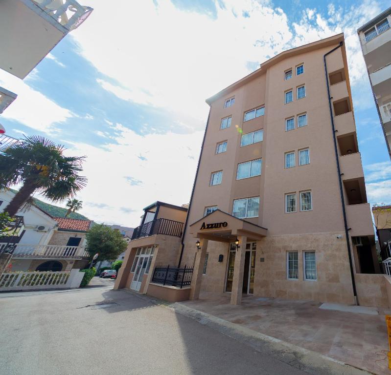 a tall building with a palm tree in front of it at Azzuro apartments Budva in Budva