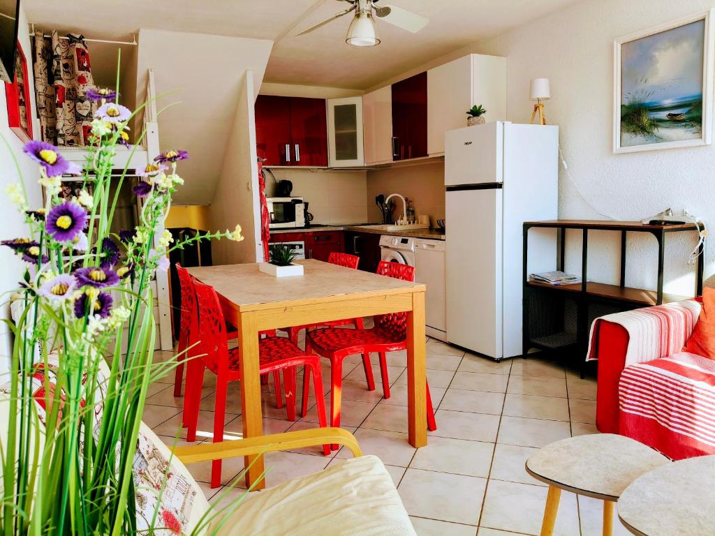une cuisine avec une table et des chaises rouges et un réfrigérateur blanc dans l'établissement Appartement T2 Duplex 4 P 35m2 avec parking, proche mer, au Grau-du-Roi