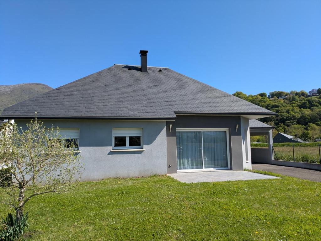 une maison avec un toit et une pelouse dans l'établissement Maison récente 6 personnes, à Argelès-Gazost