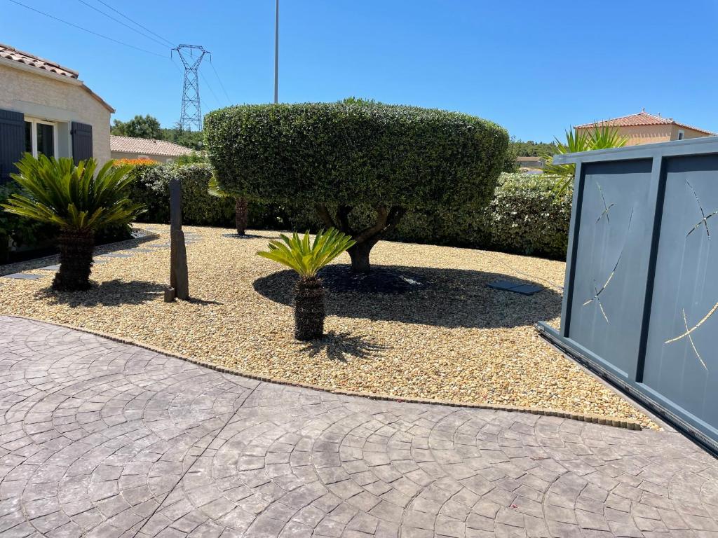 un jardin avec un arbre et des buissons à côté d'un bâtiment dans l'établissement petit paradis au soleil, à Narbonne