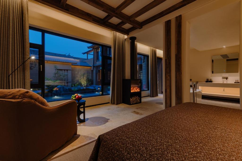 Un dormitorio con una cama y una ventana grande en Shaxi Fengyasong Village Hotel, en Diannan