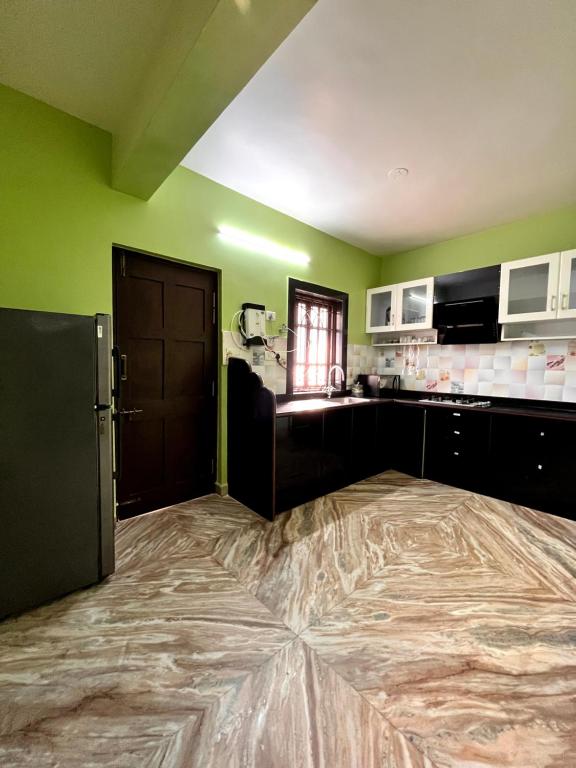Una gran cocina con paredes verdes y un refrigerador. en Nikita Retreat Stay, en Calangute