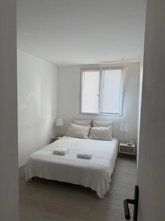une chambre blanche avec un lit avec deux serviettes dessus dans l'établissement Location proche de toute commodités à 1 minute du tramway et à 9 min de centre ville et parking gratuit dans résidence privée, à Nice