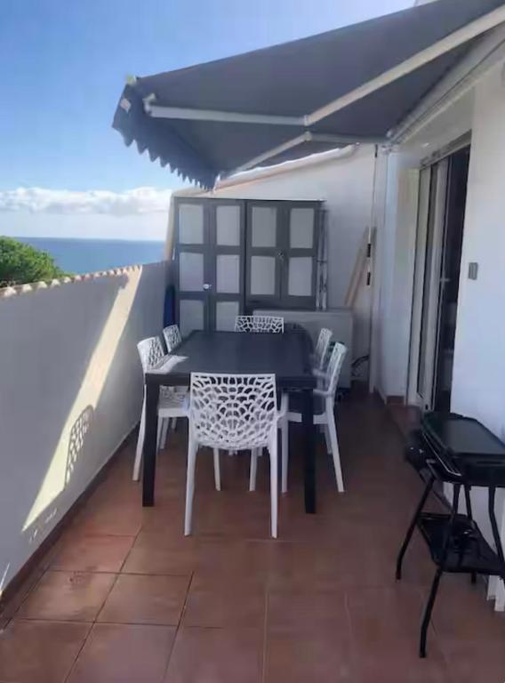 une table et des chaises sur un balcon avec l'océan dans l'établissement Appartement avec piscine vue mer et montagne, à San-Nicolao
