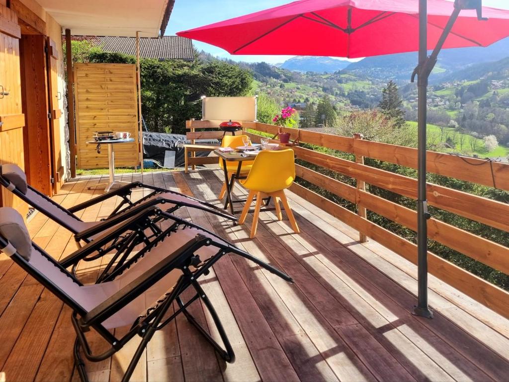 un patio avec une table, des chaises et un parasol dans l'établissement Private terrace, cosy appartement, ideal couple, bbq,relax, welcome, near La Clusaz, Grand Bornand, Annecy and lake, many sports and entertainment activities summer and winter, à Les Villards-sur-Thônes