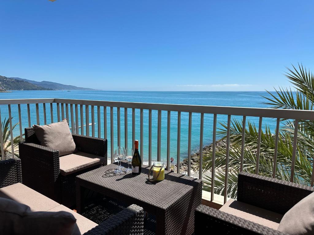 une table et des chaises sur un balcon avec l'océan dans l'établissement Stella Mare-Vue mer-clim-terrasse, à Menton
