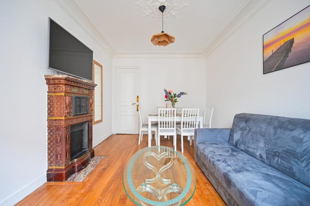 un salon avec un canapé bleu et une télévision dans l'établissement Apartment Suite Parties 17, à Paris