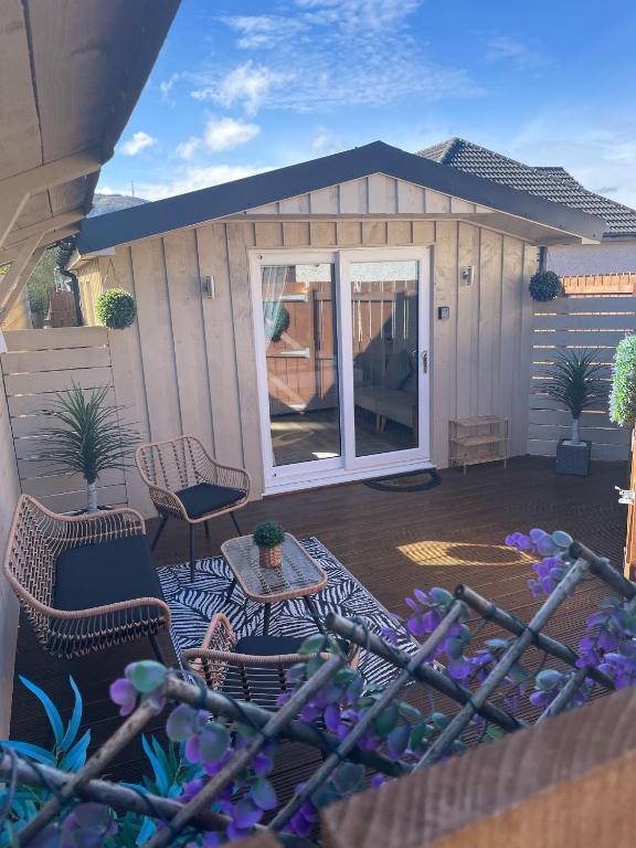 a small shed with a patio with chairs and a table at The Grove Cabin in Fort William