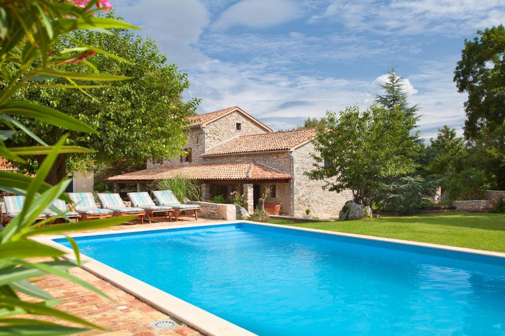 a swimming pool in front of a house at Villa Favola, a rustic retreat surrounded by beautiful nature in Vinež
