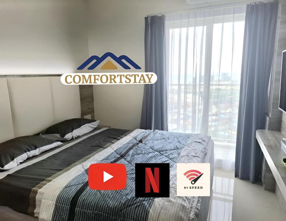 a bedroom with a bed with a comforter and a sign at COMFORTSTAY-Citra Plaza Nagoya #31-06 Sea View in Jodoh