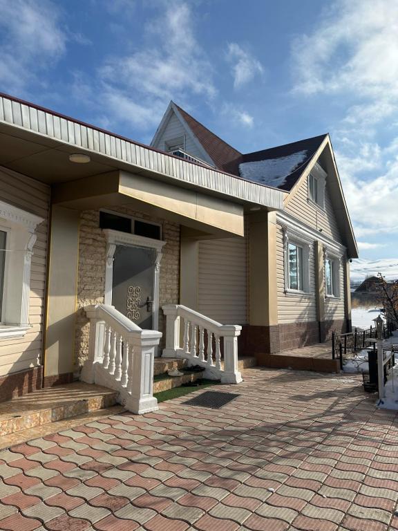 a house with a porch with a white railing at Аренда Дома in Karakol
