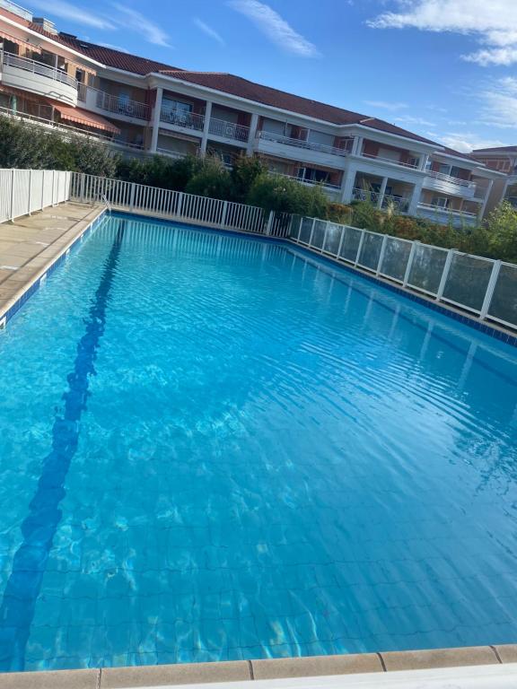 a large blue swimming pool in front of a building at 2P jardin Sud vue Lac avec piscine tennis parking privé in Le Cannet