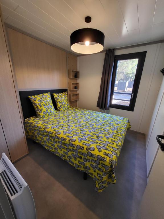 een slaapkamer met een bed met een geel dekbed en een raam bij Cottage Cap d Agde in Agde