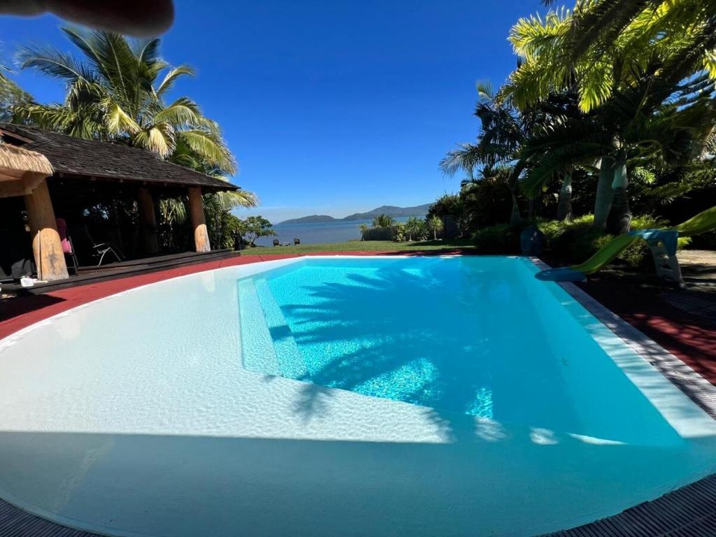 a blue swimming pool with palm trees in the background at Exceptional villa with direct beach access in Dumbéa