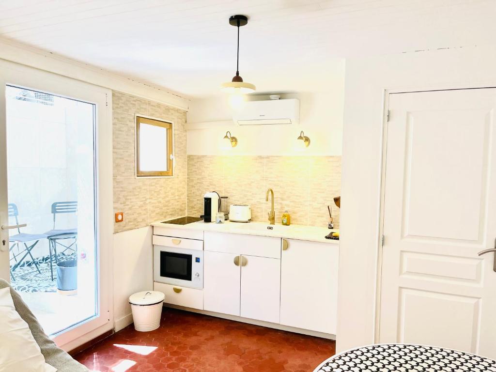 une cuisine blanche avec un évier et un micro-ondes dans l'établissement La Maison by Simone T2, à Cannes