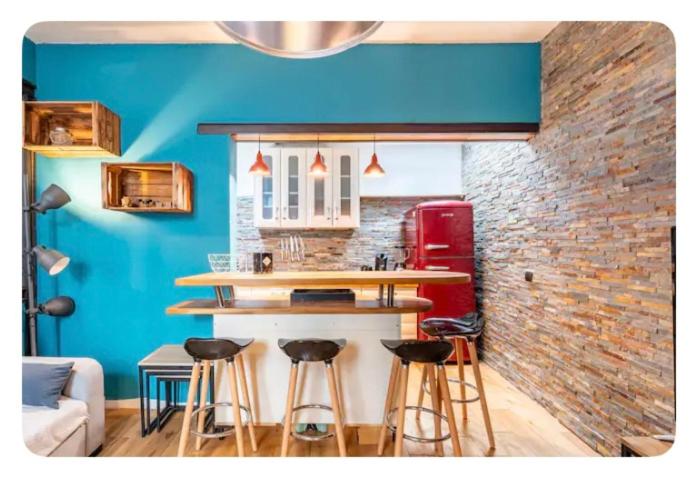 un bar dans une pièce avec un mur bleu et des tabourets dans l'établissement LE PATIO de PROVENCE en AVIGNON - hypercentre, clim, WIFI, calme, à Avignon