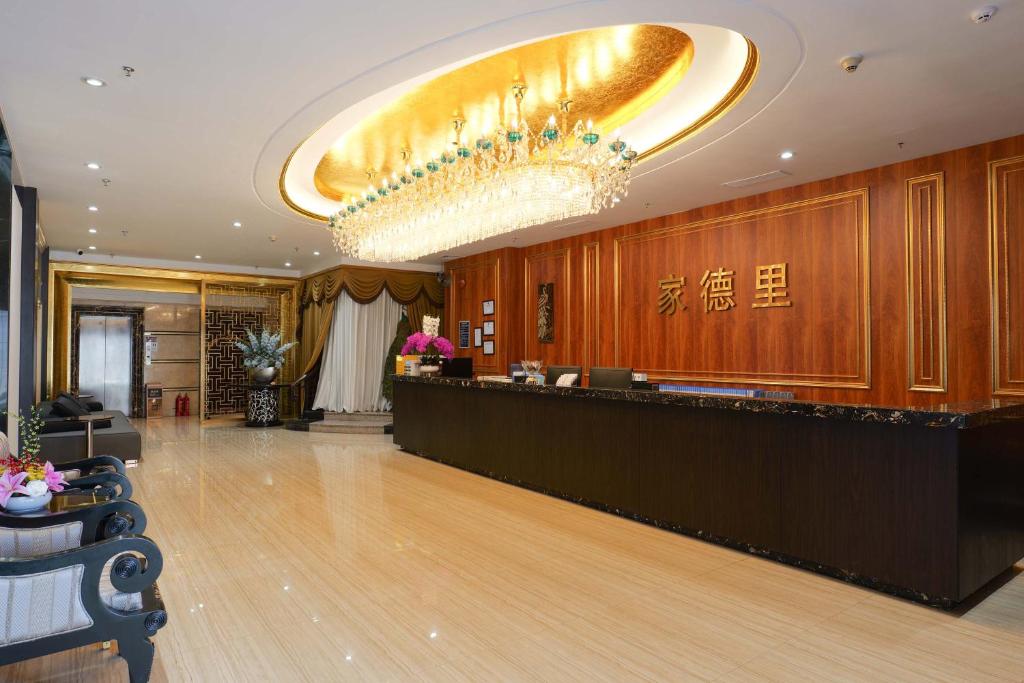 a hotel lobby with a reception desk and a chandelier at 家德里酒店Dilli home hotel in Zhongshan