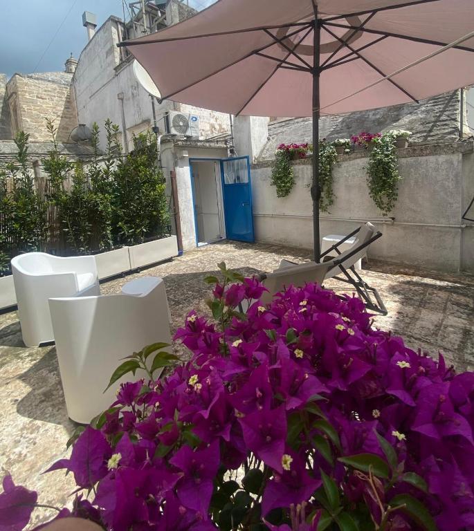 a patio with purple flowers and an umbrella at Porta Blu Apulia in Martina Franca
