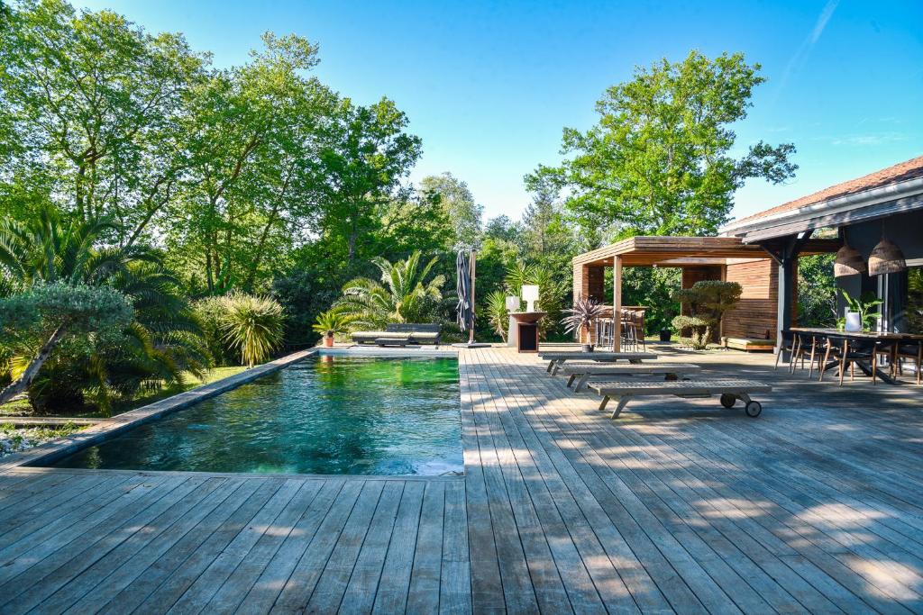 - une piscine avec bancs à côté d'une maison dans l'établissement La Cierba Villa avec piscine et jacuzzi, à Angresse