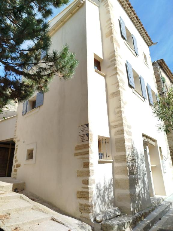 un bâtiment blanc avec un arbre devant lui dans l'établissement Maison de village avec superbe terrasse en pierre, à Caromb