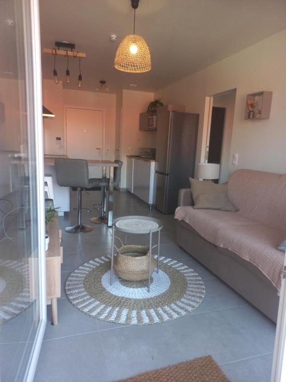 een woonkamer met een bank en een tafel bij La cabane Cosy ZEN des SABLES avec Wifi-Plage à 500m in Mimizan-Plage