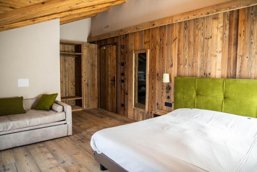 sypialnia z drewnianymi ścianami, łóżkiem i kanapą w obiekcie Hotel La Montanina w Livigno