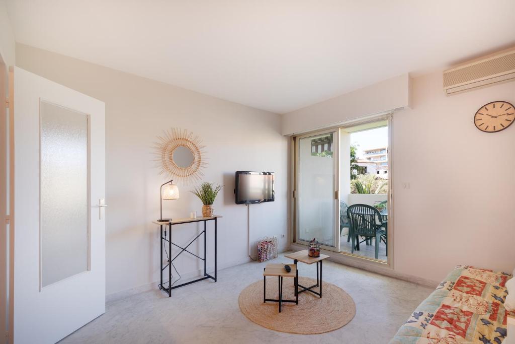 un salon avec un canapé et une horloge au mur dans l'établissement Antibes PISCINE ET TENNIS, à Antibes