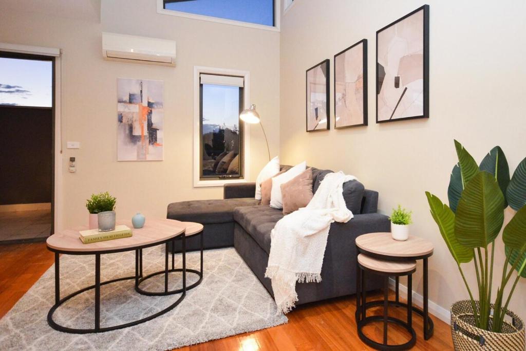 Una sala de estar con un sofá y dos mesas. en Luxury Townhouse Stay, en Melbourne
