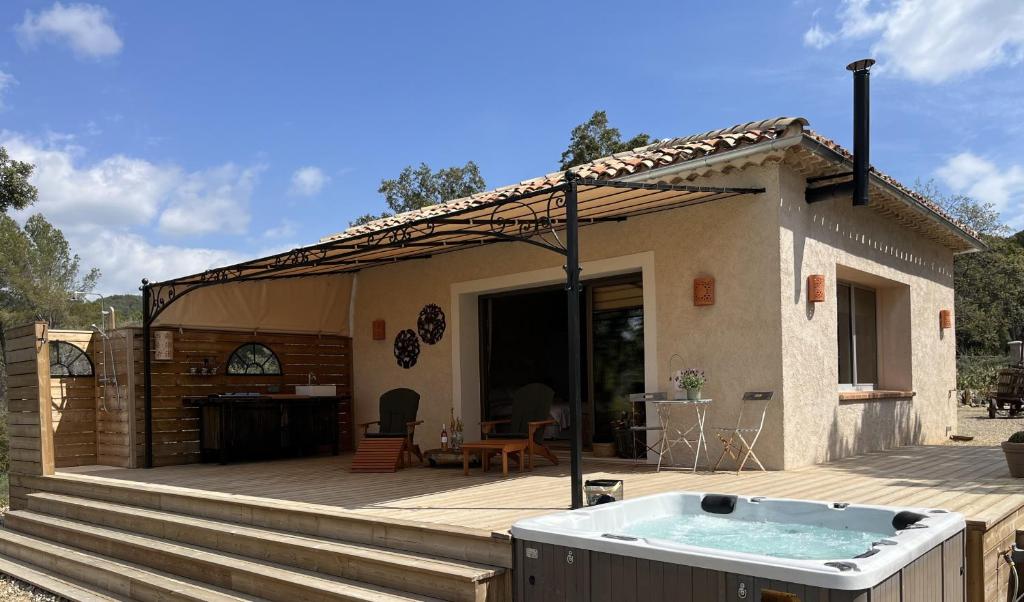 une maison avec un bain à remous sur une terrasse en bois dans l'établissement La Tour de Roubeirolle, à Tourtour