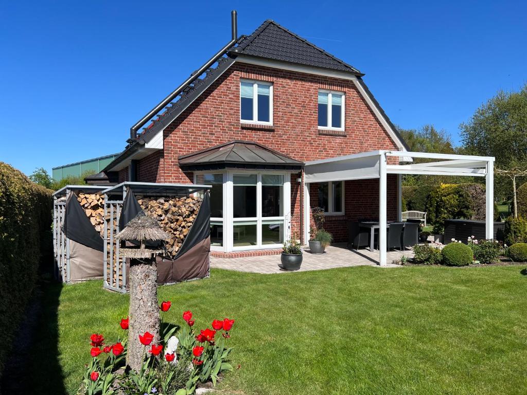 a red brick house with a whiteconservatory in a yard at Kranichstube in Rövershagen