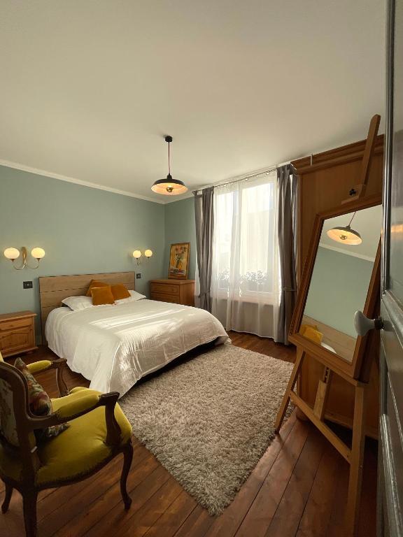 une chambre avec un lit, une chaise et un miroir dans l'établissement Appartement dans maison de ville, proche stade de France et Salon du Bourget, à La Courneuve