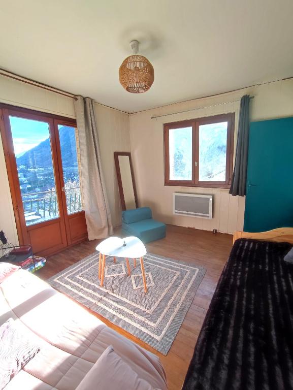 a living room with a bed and a table and windows at Saint-Michel de Maurienne, appartement de 45 m² in Saint-Michel-de-Maurienne