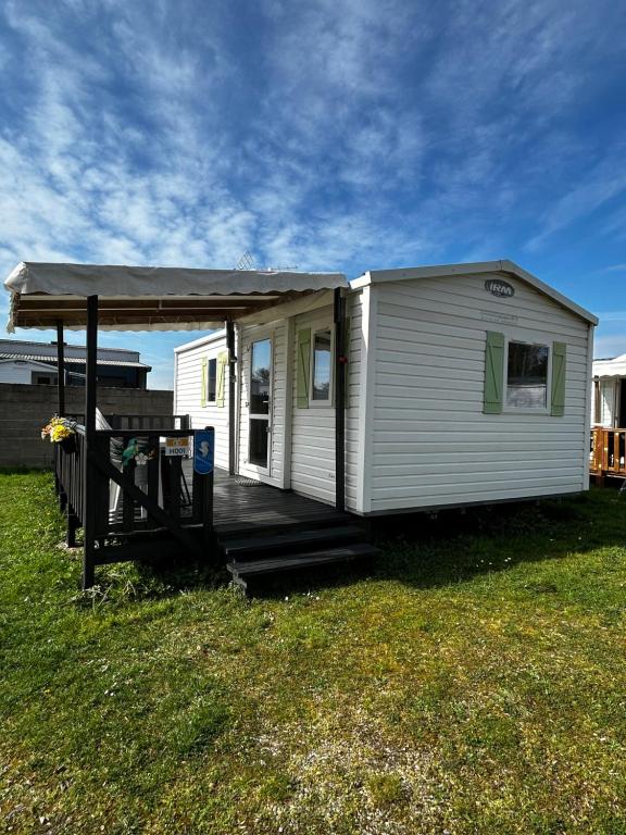 une petite maison blanche avec une terrasse couverte sur une pelouse dans l'établissement Mobilhome 5 personnes proche Europapark, à Boofzheim