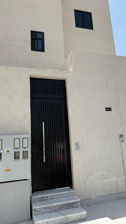 a building with a black door on the side of it at شقة بأثاث فُندقي in Al Madinah