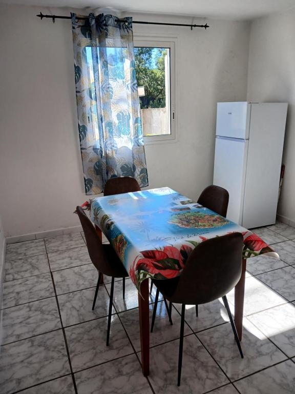 a kitchen with a table and chairs and a refrigerator at Maison au Bois-Court in Le Tampon