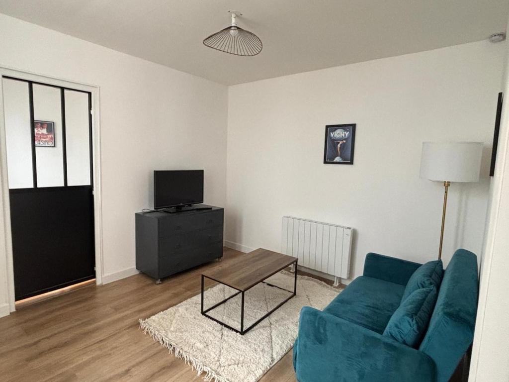 un salon avec un canapé bleu et une télévision dans l'établissement T2 Vieux Vichy, à Vichy