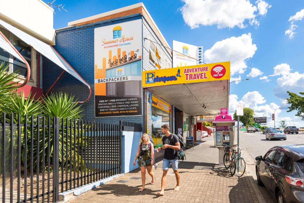 a man and woman walking down a sidewalk in front of a building at Summer House Backpackers Brisbane in Brisbane