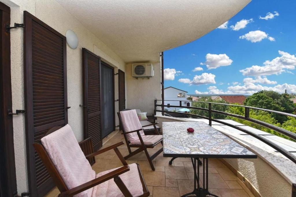 a balcony with a table and chairs and a view at Charming apartment with balcony and pool in Peroj