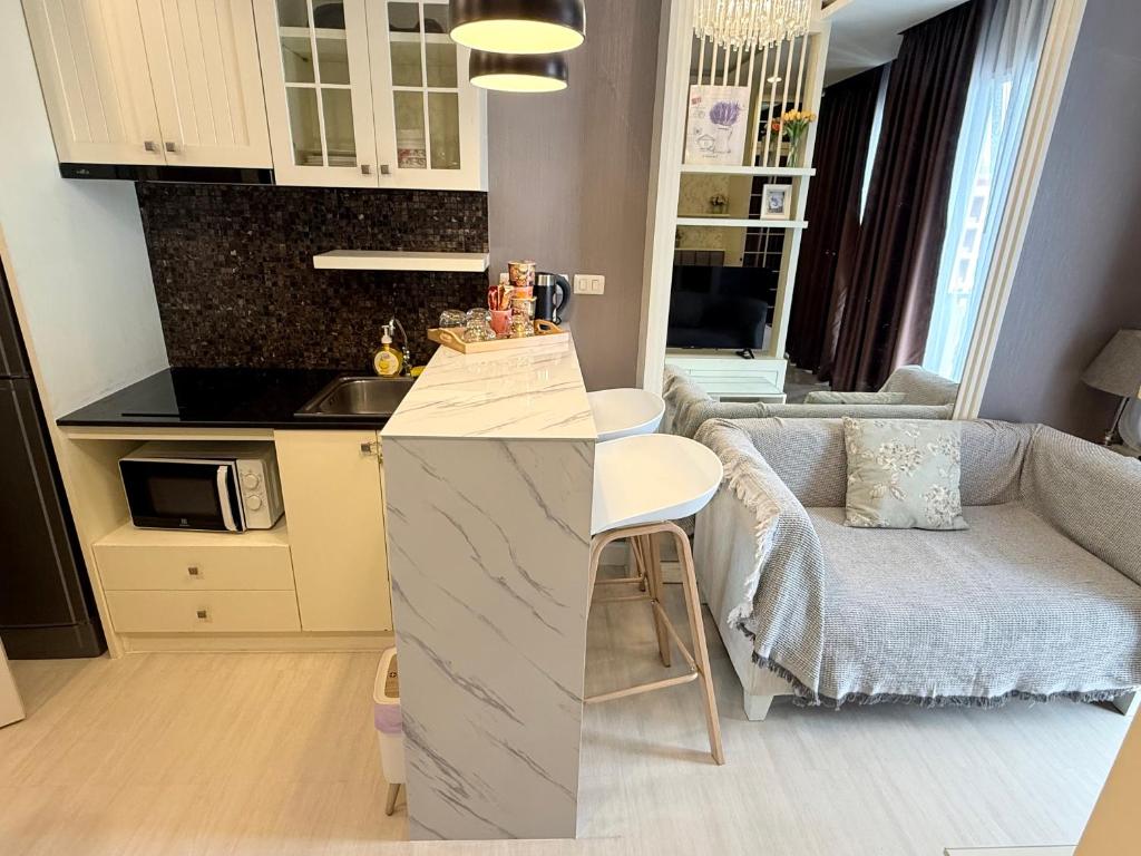 a kitchen and a living room with a couch at The Patio bangsaen miracle sea Top floor in Ban Chek