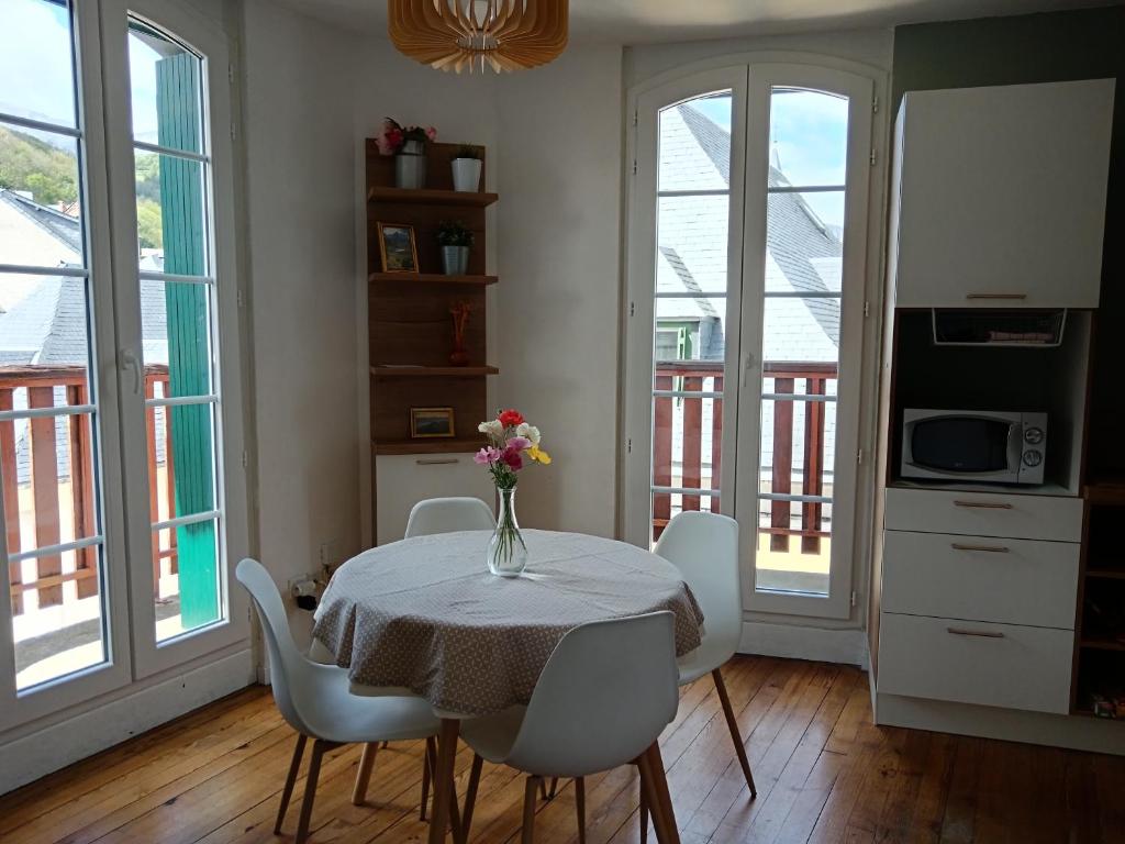 a dining room with a table with a vase of flowers on it at T2 Coeur d' Argelès-Gazost, tout à pied in Argelès-Gazost