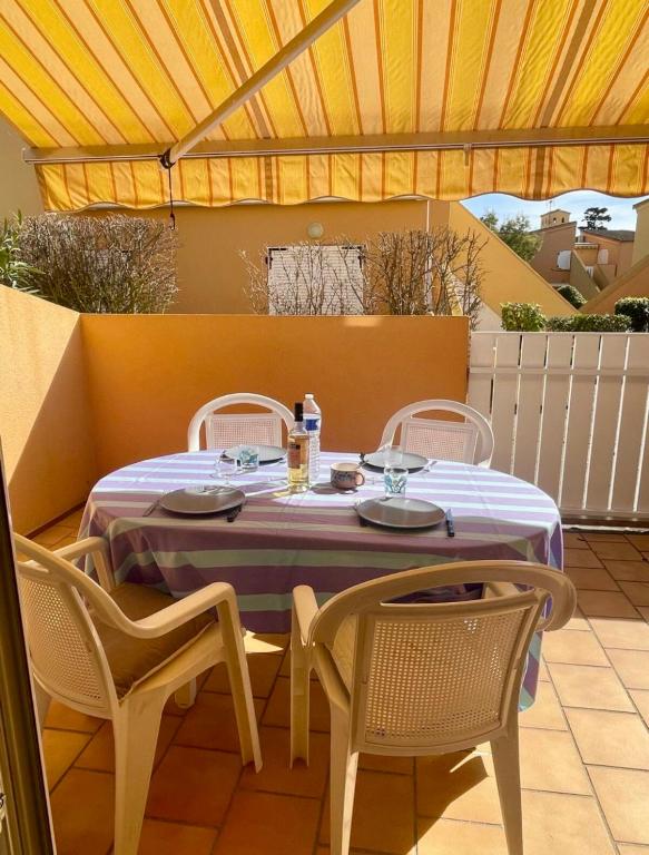une table et des chaises assises sur une terrasse dans l'établissement L'authentique - Roquille - Histoire de clés, au Cap d'Agde