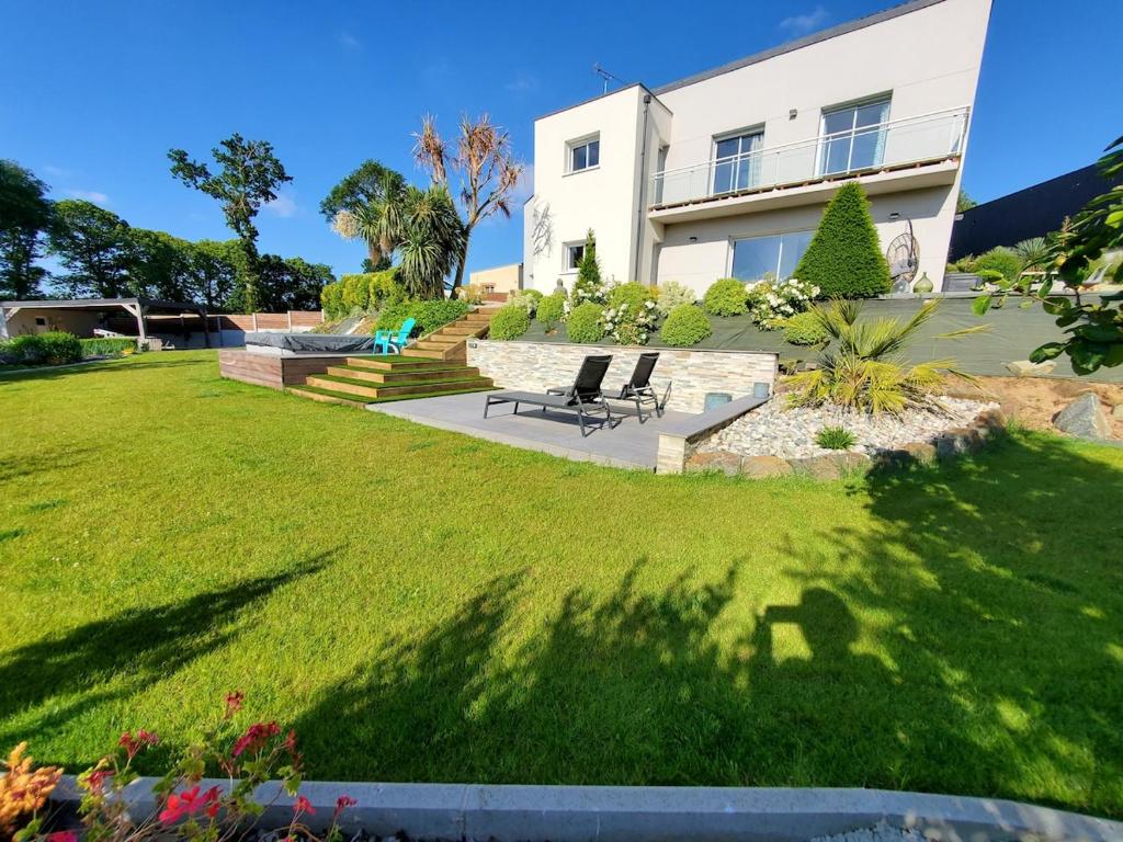 une maison avec une pelouse et un banc devant elle dans l'établissement Villa with terrace and garden, à La Méaugon