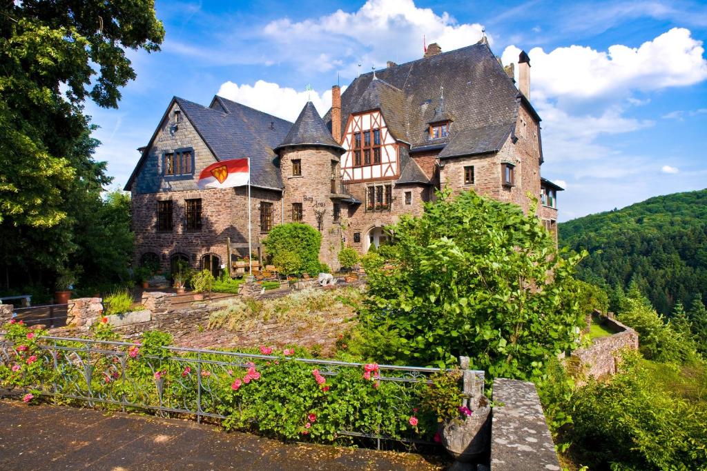 een oud kasteel bovenop een heuvel met bloemen bij Hotel Burg Arras in Alf