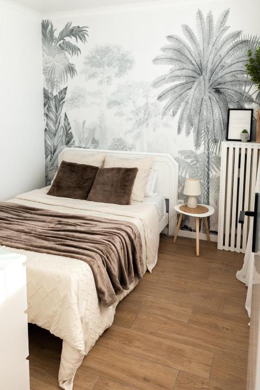 - une chambre avec un lit et une fresque murale de palmiers dans l'établissement Appartement avec climatisation, à 900 m de la plage, à Fréjus