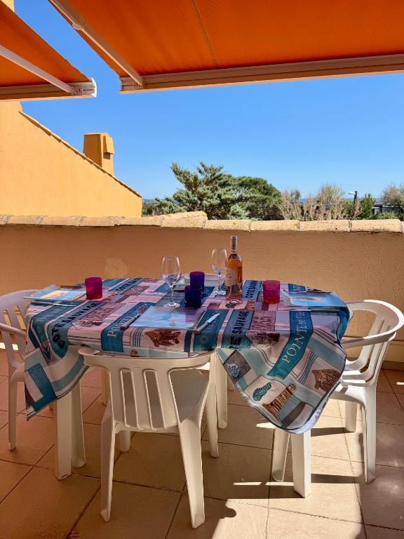 - une table avec 2 chaises et une bouteille de vin dans l'établissement Parenthèse Marine - Roquille - Histoire de clés, au Cap d'Agde